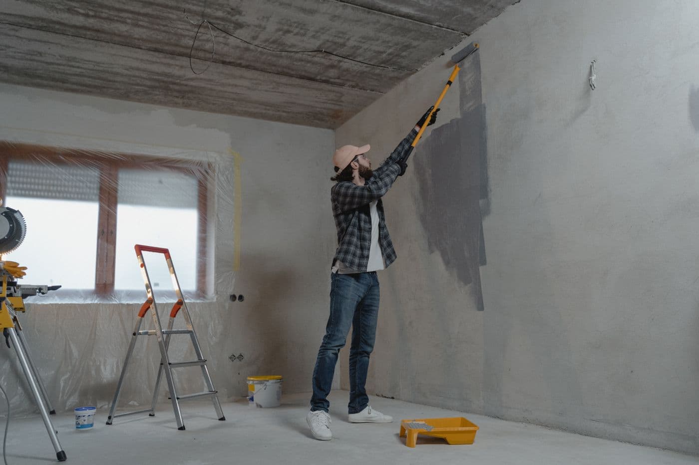 Pièce en cours de rénovation, peinture au rouleau sur un mur brut